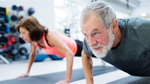 Middle aged man and woman performing push ups