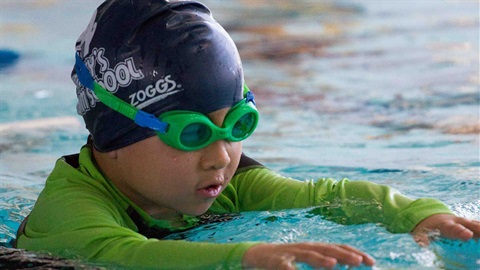 Child in the water with goggles about to swim