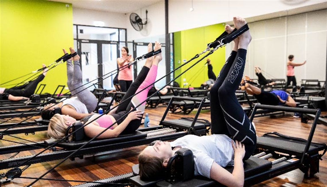 Group fitness class showing participants doing reformer pilates