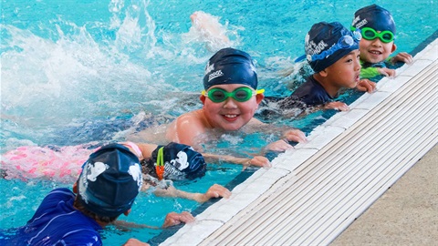 Children having fun while splashing at the side of a pool