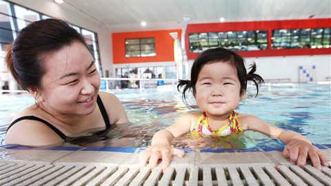 Mother with children in water holding onto edge of the pool