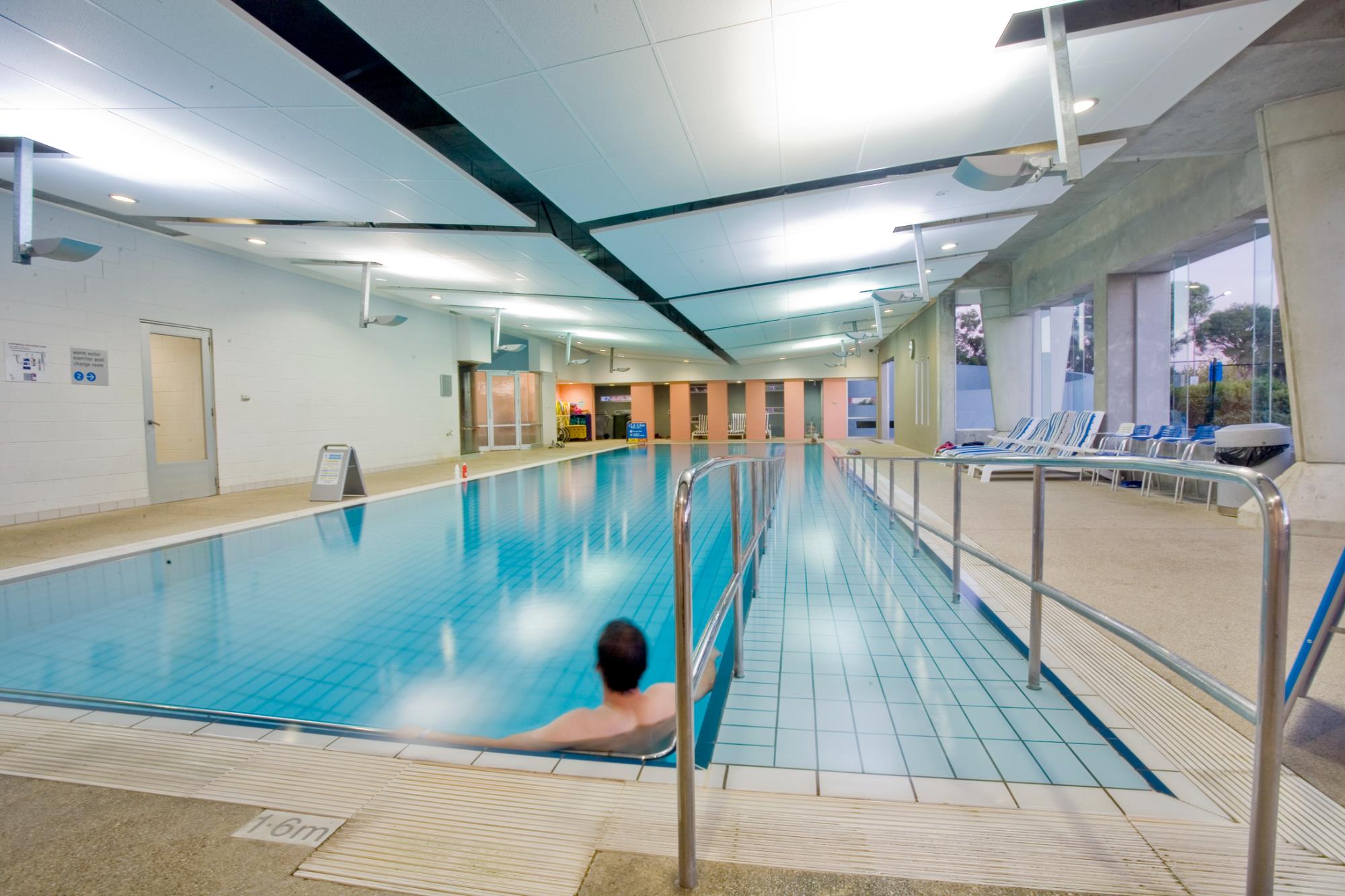 Pool with ramp entry and man relaxing against wall