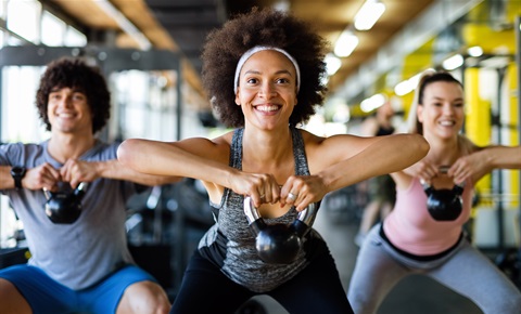 3 people lifting kettle bell weights in the gym.png